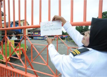 PENGAWAL keselamatan, Marsita Mustafa meletak tanda sekolah ditutup berikutan isu pencemaran bau dari Sungai Tebrau di SK Kampung Maju Jaya di Kampung Maju Jaya, Johor Bahru. – UTUSAN/RAJA JAAFAR ALI