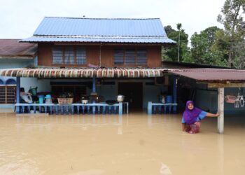 SEORANG wanita berada di hadapan rumahnya ketika air banjir menghampiri paras pinggang di Kampung Sungai Kechil, Nibong Tebal, Pulau Pinang.-UTUSAN/IQBAL HAMDAN