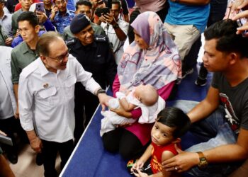 ANWAR Ibrahim menyantuni keluarga yang berlindung sementara di PPS SMK Agama Kedah ketika mengadakan lawatan banjir ke negeri ini di Alor Setar. - UTUSAN/ SHAHIR NOORDIN