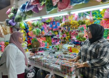 NUR Fatihah Othman (kanan) melayan pelanggan yang mengunjungi premisnya di Pasar Kedai Payang 1, Kuala Terengganu, kelmarin.