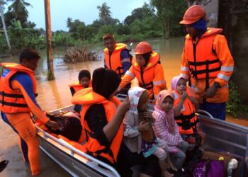 PENDUDUK yang terjejas banjir dipindahkan oleh anggota APM Pendang ke PPS Dewan Kompleks Rakan Sukan Tanah Merah di Pendang. - IHSAN APM