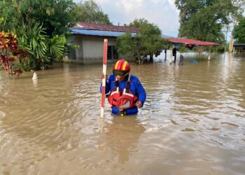 ANGGOTA Angkatan Pertahanan Awam (APM) Kubang Pasu mengukur paras air di sebuah kampung yang dilanda banjir di Kubang Pasu. - IHSAN APM