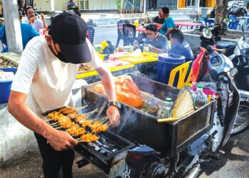 MUHAMMAD ASHRAF Salleh membakar sate atas motosikal sebaik sahaja mendapat pesanan pelanggan di Taman Ayer Keroh Height, 
Ayer Keroh, Melaka. – MINGGUAN/SYAFEEQ AHMAD