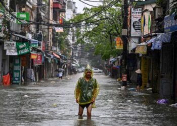 Seorang lelaki memakai ponco ketika melalui sebatang jalan yang dinaiki air di Hanoi, Vietnam selepas negara itu dilanda Taufan Yagi yang tempiasnya turut dirasai di kawasan utara tanah air apabila angin bertiup kencang. - AFP