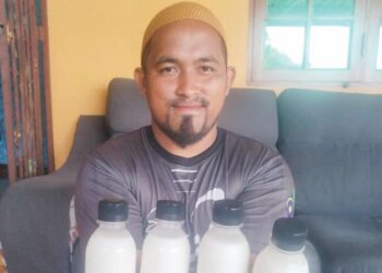 MUHAMMAD Ikram Borahim menunjukkan susu kambing yang siap dibotolkan di kediamannya di Kampung Jabi, Jerteh, Besut, Terengganu, semalam.