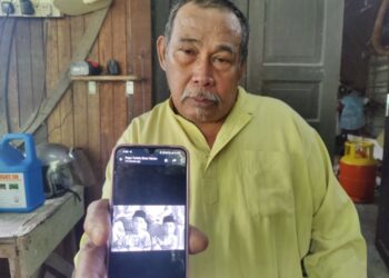 MUHAMMAD Yahya menunjukkan gambar dua anaknya yang lemas di kawasan parit di Kampung Melaka, Tanjong Karang di Kuala Selangor, Selangor. - MINGGUAN/ISKANDAR SHAH MOHAMED