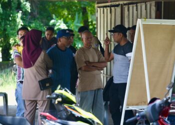 ISMAIL Baharom (dua kanan) mendengar penerangan pegawai polis di lokasi pencarian adiknya, Sabari di Kampung Lubuk Batu, Kubang Pasu. - UTUSAN/ SHAHIR NOORDIN