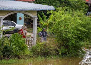 PENDUDUK, Sharina Hashim mengambil peluang memancing ikan darat di hadapan rumahnya yang digenangi air akibat banjir di Kampung Banggol Besi, Pendang. - UTUSAN/ SHAHIR NOORDIN