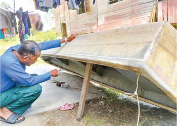 RAJA Shahrin Ismail memeriksa bot miliknya yang menjadi kenderaan utama setiap kali banjir melanda  Kampung Seberang Batu Badak, Segamat.