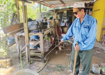 ISA Samat membersihkan kawasan rumahnya yang dinaiki banjir di Kampung Tehel, Bemban, Melaka. – UTUSAN/MUHAMMAD SHAHIZAM TAZALI