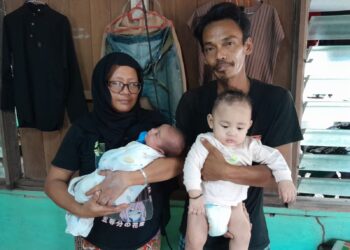 Shamiezan Abd. Razak mendukung anaknya, Muhammad Azriq Afiq dan isterinya, Norashikin Othman memegang cucunya, Muhamad Ayden Aiys di rumahnya di Kampung Batu Hampar, Sanglang, di Pontian, Johor. – UTUSAN/MUHAMMAD ZIKRI