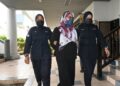 TERTUDUH diiringi anggota polis ketika dihadapkan ke Mahkamah Sesyen Ayer Keroh, Melak hari ini..