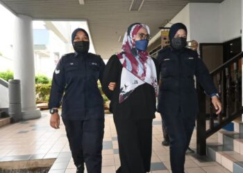 TERTUDUH diiringi anggota polis ketika dihadapkan ke Mahkamah Sesyen Ayer Keroh, Melak hari ini..