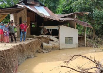 HAMINAH Ngah (dua kiri) bersama keluarganya menunjukkan sebahagian rumahnya yang roboh ke dalam Sungai Ketil ketika banjir di Kampung Batu 60, Tanjung Pari, Baling, Kedah semalam.