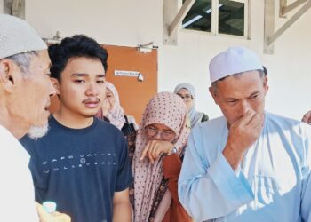 MD. Tukirin Saringat (kanan) menahan sebak ketika menuntut jenazah anaknya, Muhammad Akmal di Unit Forensik Hospital Dungun, hari ini. - UTUSAN/NIK NUR IZZATUL HAZWANI NIK ADNAN