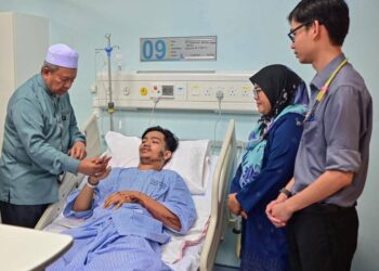 MALIAMAN Kassim (kiri) melihat kesan kecederaan yang dialami Muhammad Ammar Danish Mohammad Ridhuan dalam kemalangan meragut nyawa tiga rakannya di Hospital Dungun, hari ini. - UTUSAN/PUQTRA HAIRRY ROSLI