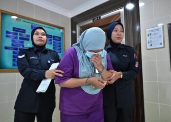 NOORAINI Remali (tengah) yang dituduh membunuh rakan kongsinya dibawa keluar dari Mahkamah Tinggi Kuala Terengganu, hari ini.  - UTUSAN/TENGKU DANISH BAHRI TENGKU YUSOFF