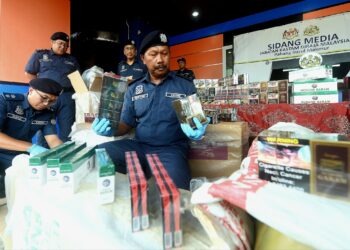 MOHD ASRI Seman (kanan) menunjukkan sebahagian daripada rokok dan minuman keras yang dirampas dalam sidang akhbar di Wisma Kastam di Kuantan, Pahang. - FOTO/SHAIKH AHMAD RAZIF