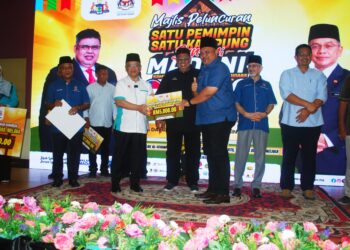 AB. RAUF Yusoh dan  Mohd. Na'im Mokhtar menyampaikan replika cek RM5,000 kepada wakil Sekolah Kebangsaan (SK) Tanjung Bidara pada Majlis Perasmian Program Satu Pemimpin Satu Kampung Santuni Madani di Kompleks al-Khawarizmi, Masjid Tanah, Melaka. - UTUSAN/AMRAN MULUP