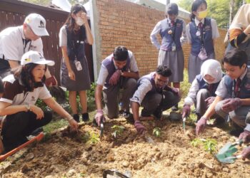 CARMEN Loo (kiri) membantu pelajar dari Adcote Matrix Malaysia menanam pokok pada Majlis Pelancaran Club-EcoGrow Garden di Bandar Sri Sendayan, Seremban hari ini.-UTUSAN/NUR SHARIEZA ISMAIL.