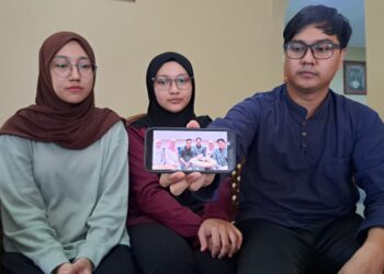 MUHAMMMAD Amir Hakimi (kanan) bersama dua kakaknya menunjukkan gambar kenangan bersama bapa mereka ketika ditemui di Kampung Mengkuang Tengah di Kuala Pegang, Baling.