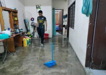 ANAK-anak Razak Mohamad membersihkan rumahnya di Jalan Talapia yang dimasuki air akibat banjir kilat petang ini.