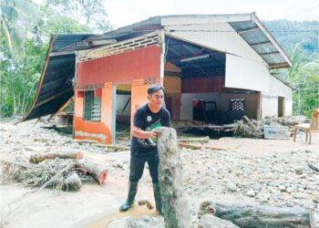 SEORANG penduduk membersihkan kawasan rumahnya yang dipenuhi batang pokok dibawa banjir lumpur. Pokok-pokok itu dipercayai ditebang melalui penerokaan kawasan hutan simpan.