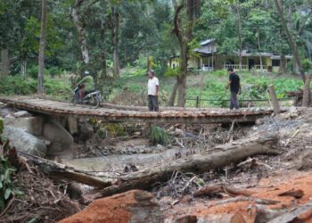 PENDUDUK menggunakan jambatan sementara yang dibuat secara gotong-royong menggunakan kayu bagi menggantikan jambatan besi yang dihanyutkan banjir di Kampung Teluk Rambong, Mukim Siong di Baling.