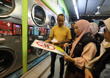 Norhayati memberikan tanda larangan merokok terbaharu kepada pemilik kedai ketika operasi di Kampung Baru. UTUSAN/AMIR KHALID