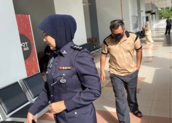 MUHAMMAD Syafiq Stewart (belakang) hadir ke Mahkamah Sesyen Seremban hari ini bagi didakwa atas tiga pertuduhan menyamar sebagai peguam bela berkelayakan dengan menipu mangsa di Kompleks Mahkamah Seremban sejak 2021. - UTUSAN/NOR SHAFAWATI YUP