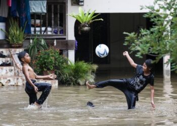 DUA kanak-kanak bermain bola dalam air ketika rumah mereka dilanda banjir buat kali ketiga di Kampung Lengkuas Mukim Derang, Pokok Sena, Kedah, semalam. – UTUSAN/SHAHIR NOORDIN