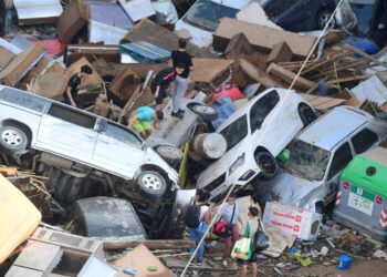 ORANG ramai memanjat timbunan kereta yang dihanyutkan oleh banjir di Sedavi, selatan Valencia, timur Sepanyol, semalam.- AFP