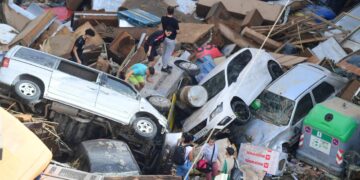 ORANG ramai memanjat timbunan kereta yang dihanyutkan oleh banjir di Sedavi, selatan Valencia, timur Sepanyol, semalam.- AFP