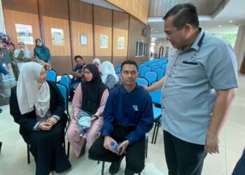 DR. Sharifudin Md. Shaarani (kanan) menyantuni Hariz yang cedera di kepala dan ahli keluarga selepas mereka terlibat kemalangan ketika dalam perjalanan ke USIM, Nilai, Seremban hari ini.-UTUSAN/NOR SHAFAWATI YUP.