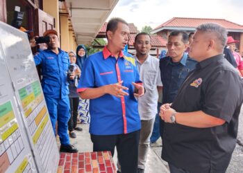 RAIS Yasin (kanan) mendengar taklimat ketika melawat PPS SK Tehel, Bemban, Melaka. - UTUSAN/MUHAMMAD SHAHIZAM TAZALI