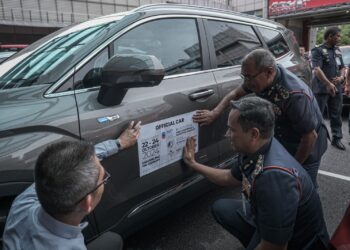 NOR Hisham Mohammad manampal pelekat rasmi ketika Majlis Penyerahan Kenderaan Rasmi Proton kepada JBPM di Putrajaya. - UTUSAN/FAIZ ALIF ZUBIR