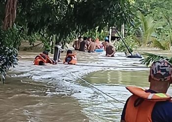 Anggota bomba menyelamatkan tiga mangsa yang berpaut pada pokok selepas rumah mereka di Kampung Haji Abas, Baling dilanda banjir kilat. - IHSAN JBPM KEDAH