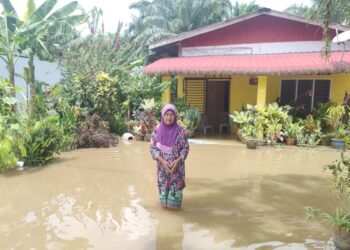 SITI Khatijah Lampam meredah banjir di laman rumahnya yang ditenggelami air akibat air laut pasang besar di Kampung Parit 16 Tanjung Medan, Sungai Panjang, di Sabak Bernam, Selangor, semalam. - UTUSAN / ISKANDAR SHAH MOHAMED