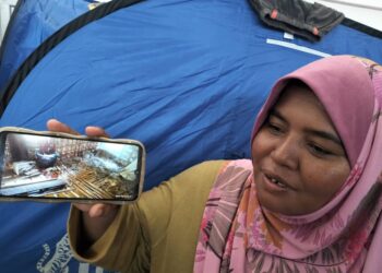 ZALINAH Zabidi menunjukkan gambar keadaan rumah buluhnya yang rosak teruk dalam kejadian banjir di Kampung Chenein, Sungai Siput. - UTUSAN