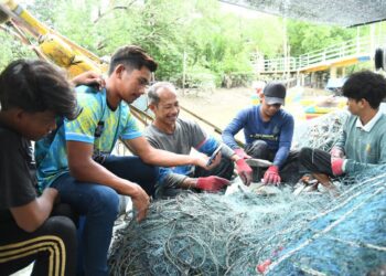 ZAKARIA Ibrahim, 48, (tiga dari kiri) bersama beberapa nelayan melakukan kerja-kerja pemindahan ikan selepas pulang dari laut di Kampung Pulau Ketam, Kuala Perlis, Perlis, semalam. -UTUSAN/IZLIZAN OTHMAN