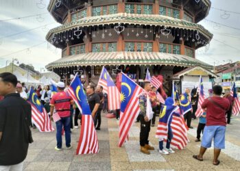 PESERTA mengibar Jalur Gemilang di Menara Teluk Intan hari ini susulan insiden tular kumpulan mengibar bendera negara China di hadapan bangunan warisan itu, kelmarin. - UTUSAN