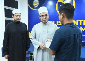 AHMAD (kanan) menerima agihan zakat daripada Mufti Perlis, Datuk Dr. Mohd. Asri Zainul Abidin untuk memulakan hidup baharu di pejabat Perlis Centre of Wisdom, Kangar, Perlis, semalam. – UTUSAN/IZLIZAN OTHMAN