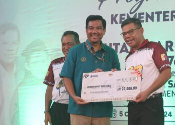 SAIFUDDIN Nasution Ismail menyampaikan sumbangan KDN kepada KMEK yang diterima  Adie Suri Zulkifli pada Program Sua Mesra Bersama KDN dan Sambutan Hari Pendaftaran Negara Ke-76 di SK Permatang Pasir, Bandar Baharu.