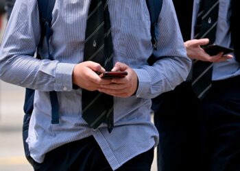 SEORANG pelajar sekolah di Melbourne sedang melayan telefon pintar ketika Australia berusaha melarang kanak-kanak bawah 16 tahun daripada media sosial.- AFP