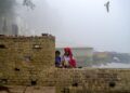 KANAK-kanak lelaki menyalakan lampu di tebing sungai Yamuna yang diselubungi kabus di New Delhi.-AFP