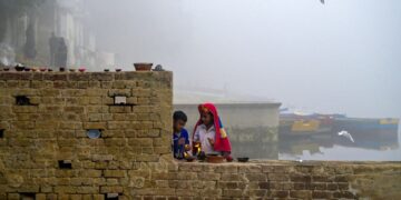 KANAK-kanak lelaki menyalakan lampu di tebing sungai Yamuna yang diselubungi kabus di New Delhi.-AFP