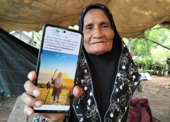 FATIMAH Mohd. Ali menunjukkan gambar ketika berada di puncak Bukit Maras ketika ditemui di Kampung Kebor Besar, Kuala Nerus, semalam. – UTUSAN/KAMALIZA KAMARUDDIN