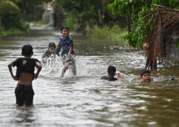 SEKUMPULAN kanak-kanak mengambil kesempatan bermain banjir di Kampung Rawai, Marang, hari ini. - UTUSAN/PUQTRA HAIRRY