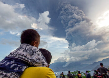 Residents watch the eruption of Mount Lewotobi Laki Laki from Eputobi village in Titihena, East Nusa Tenggara, on November 8, 2024. (Photo by Bayu ISMOYO and ARNOLD WELIANTO / AFP)