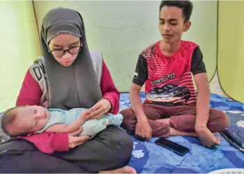 MOHAMAD  Mazriel Naim Mazlan bersama isteri, Nurul Ain Nadhirah Zolzairi dan bayi mereka berusia dua bulan di PPS Dewan Orang Ramai Kampung Tok Machang di Raub, Pahang.